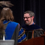 Faculty member smiles as he receives an award